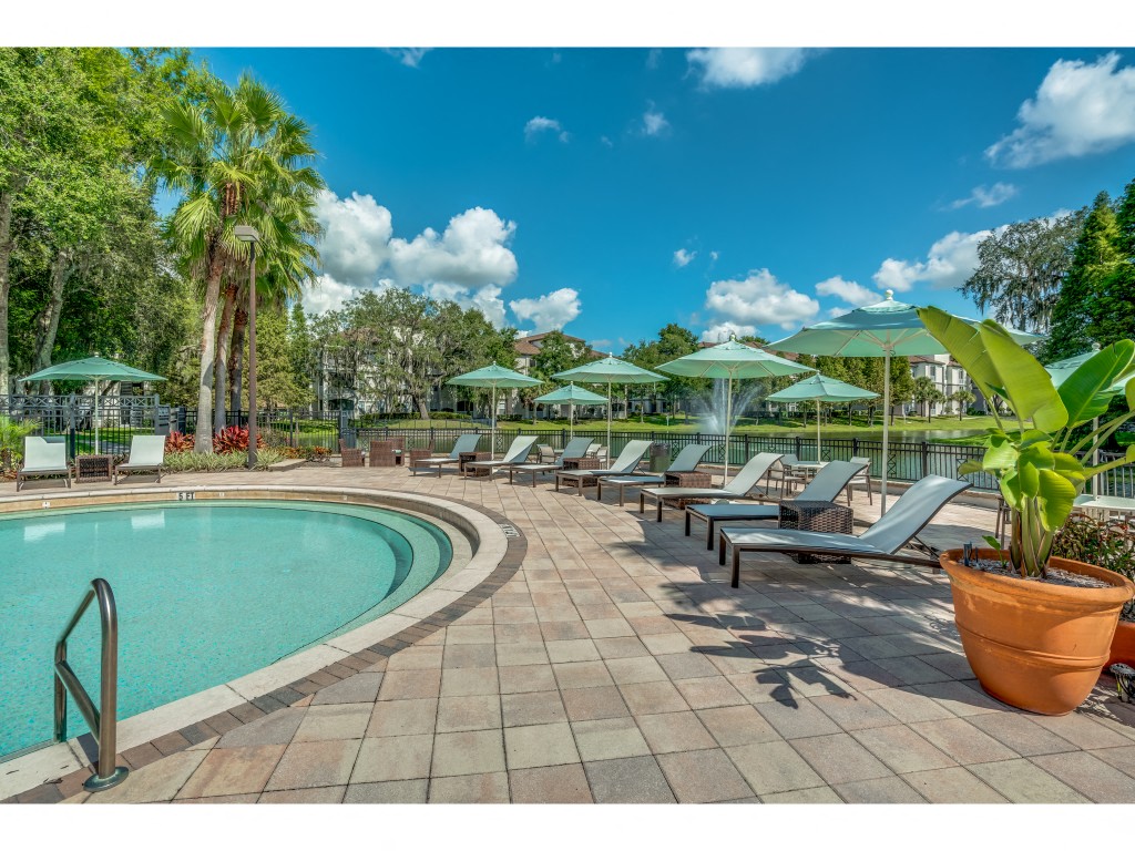 a pool with lounge chairs and umbrellas next to a resort pool