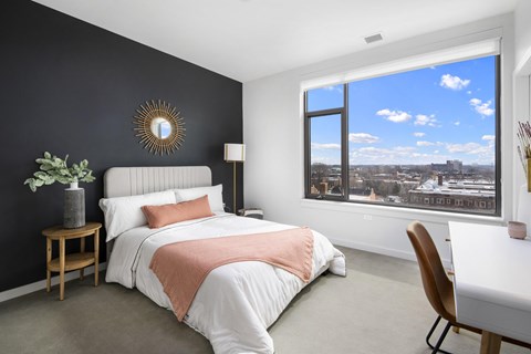 A bedroom with a large bed and a view of the city through the window.