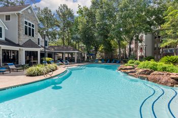 A large swimming pool in a backyard with a house and trees in the background.