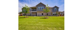 a large lawn in front of a house with trees