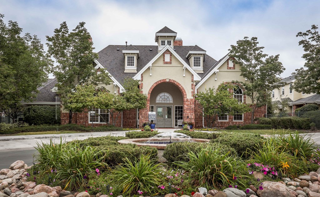 the front of a house with a fountain and gardens