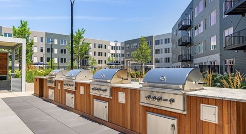 A row of outdoor BBQs are lined up on a patio.