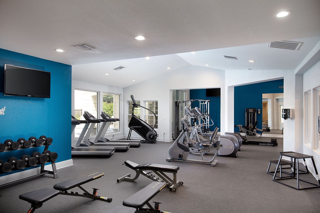 Apartments Near Historic Overland Park - The Highlands - Fitness Center with Free Weights, Bench Presses, Cardio Machines, TV, And Large Windows