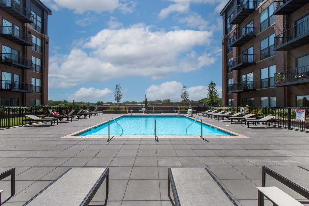 Maple Street Lofts - Big Pool with Deck, and Lounge Chairs, Surrounded by Apartment Building.