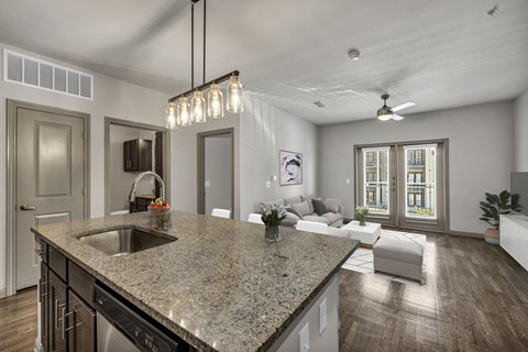 an open kitchen and living room with a granite counter top