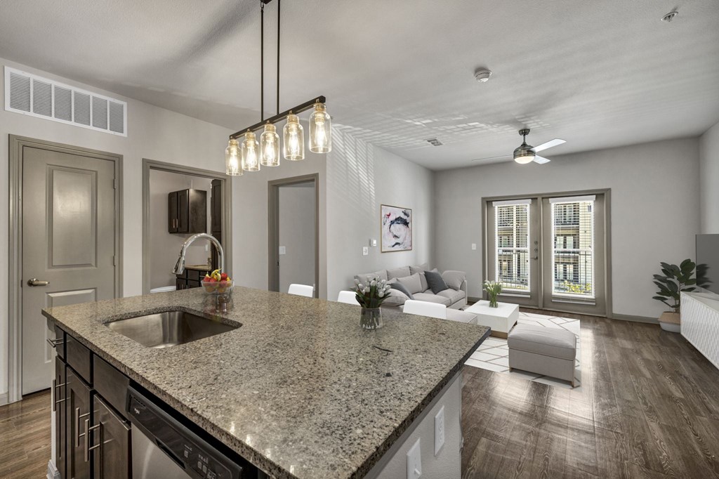 an open kitchen and living room with a granite counter top