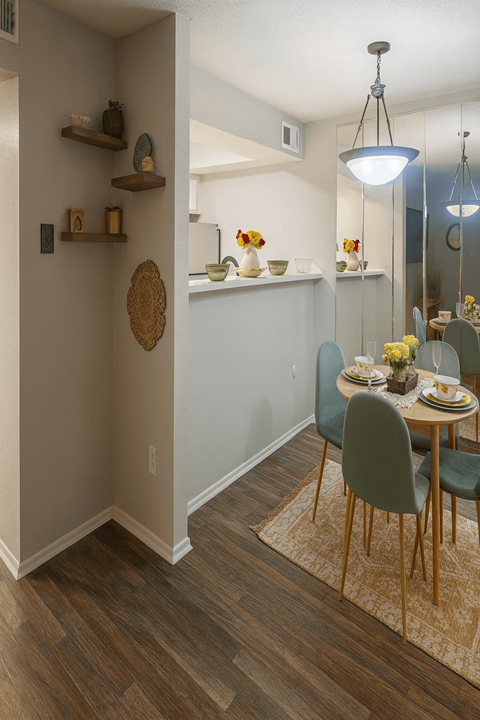 A dining room with a table set for two and a rug on the floor.