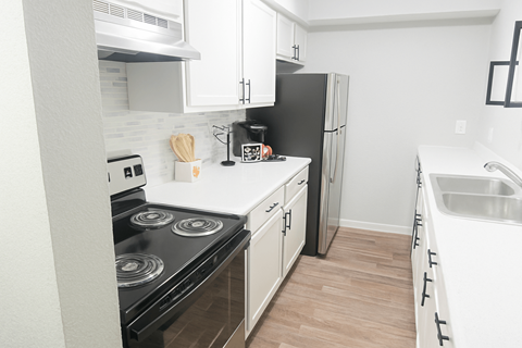 A kitchen with black appliances and white cabinets.