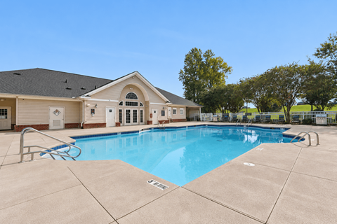 A swimming pool in front of a building with a clear blue sky.
