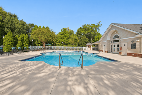 A large outdoor swimming pool with a diving board and a building in the background.