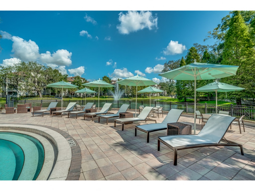 a pool with lounge chairs and umbrellas next to a swimming pool