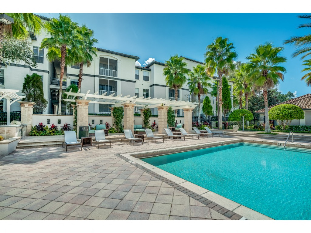 a large swimming pool in front of a building with palm trees