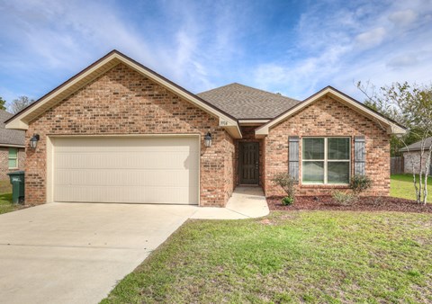 A brick house with a white garage door and a brown roof.