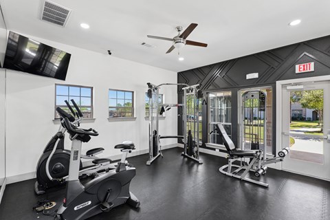 A gym with a variety of equipment including a stationary bike, a rowing machine, and a treadmill.