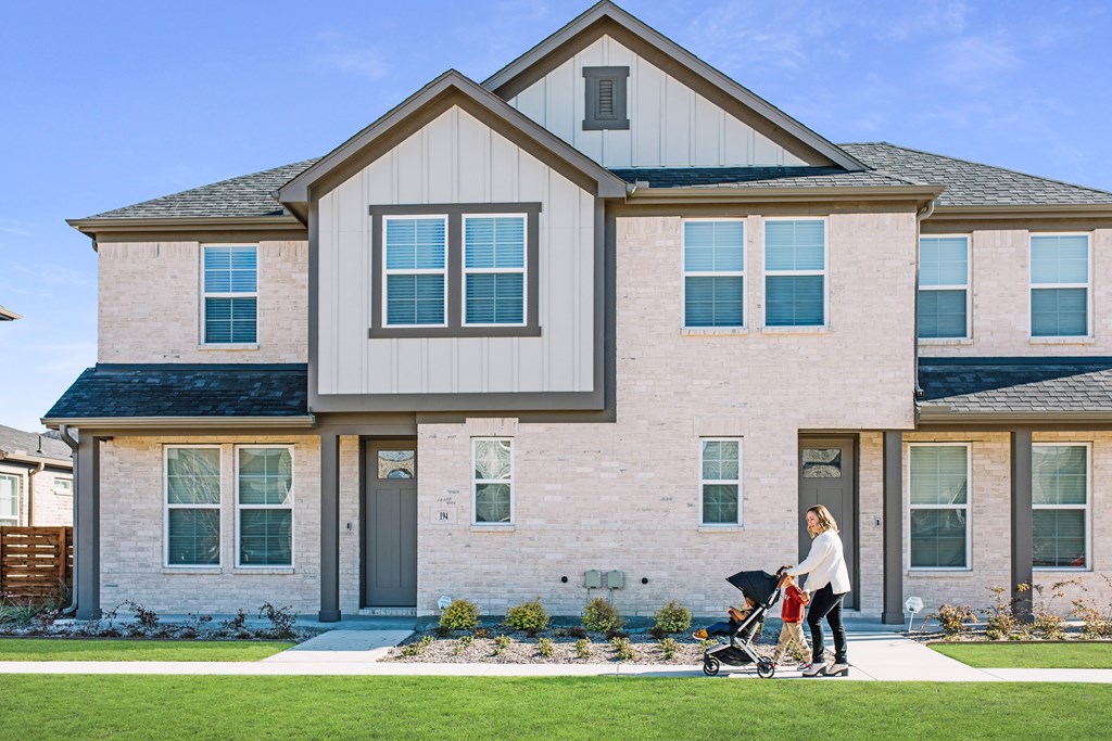 a woman pushing a stroller in front of a house