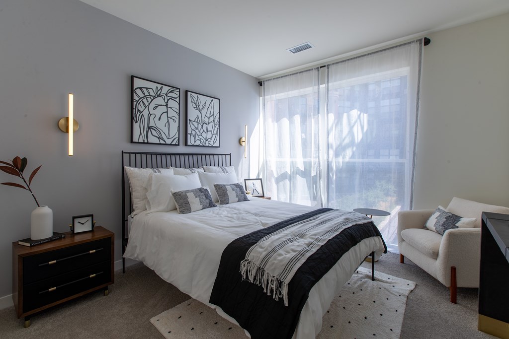 Maple Street Lofts - Bedroom with Two-Toned Paint, Bed, Dresser, Chair, Nightstand, and Window.