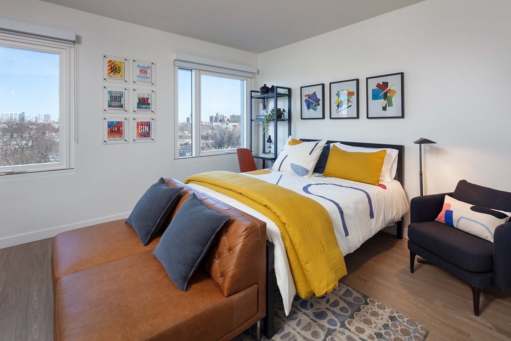 Luxury Apartments in Chicago for Rent - North + Vine - Bedroom with Bed, Nightstand, Floor Lamp, Dresser, and Large Windows.