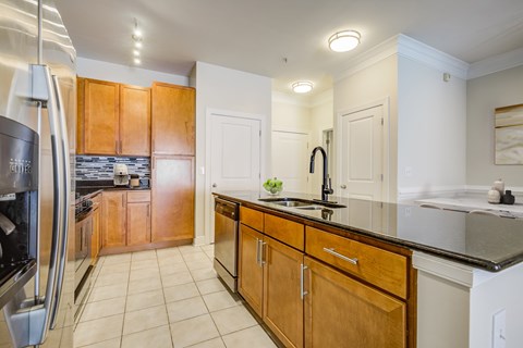 A kitchen with wooden cabinets and a black fridge.