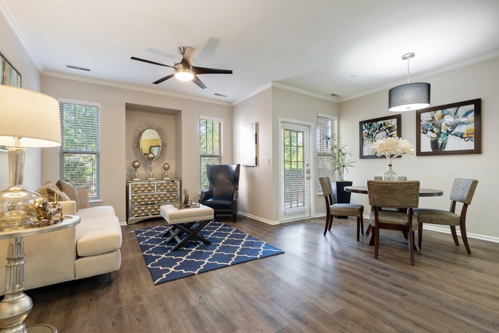 Pet-Friendly Apartments in Bolingbrook IL - The Meadows at River Run - Open, Spacious Living Area with Couch, Carpet, Ceiling Fan, Coffee table, Silver Decor, Lamps, Window, and Dining Table