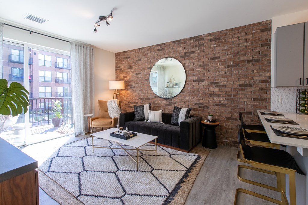 Maple Street Lofts - Spacious Living Room with Expansive Sliding Glass Door, Brick Accent Wall, and Furniture.