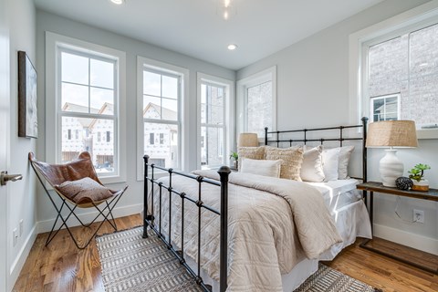 A bedroom with a large bed and a chair by the window.