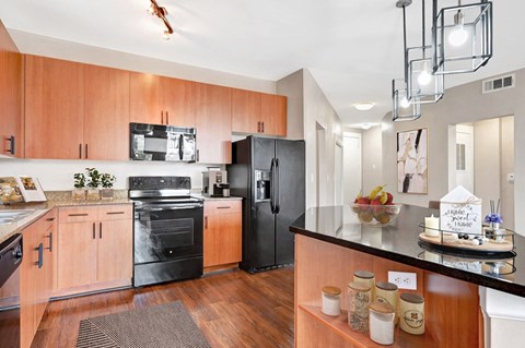 A modern kitchen with wooden cabinets and black appliances.