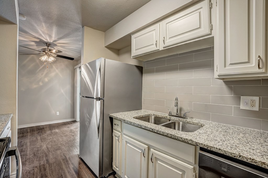 a kitchen with white cabinets and a stainless steel refrigerator