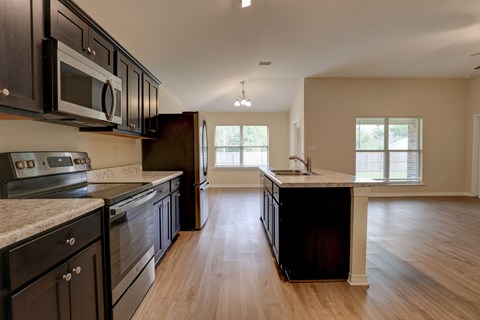 A kitchen with black cabinets and a marble countertop.