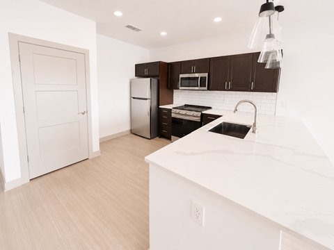 A kitchen with white countertops and dark brown cabinets.