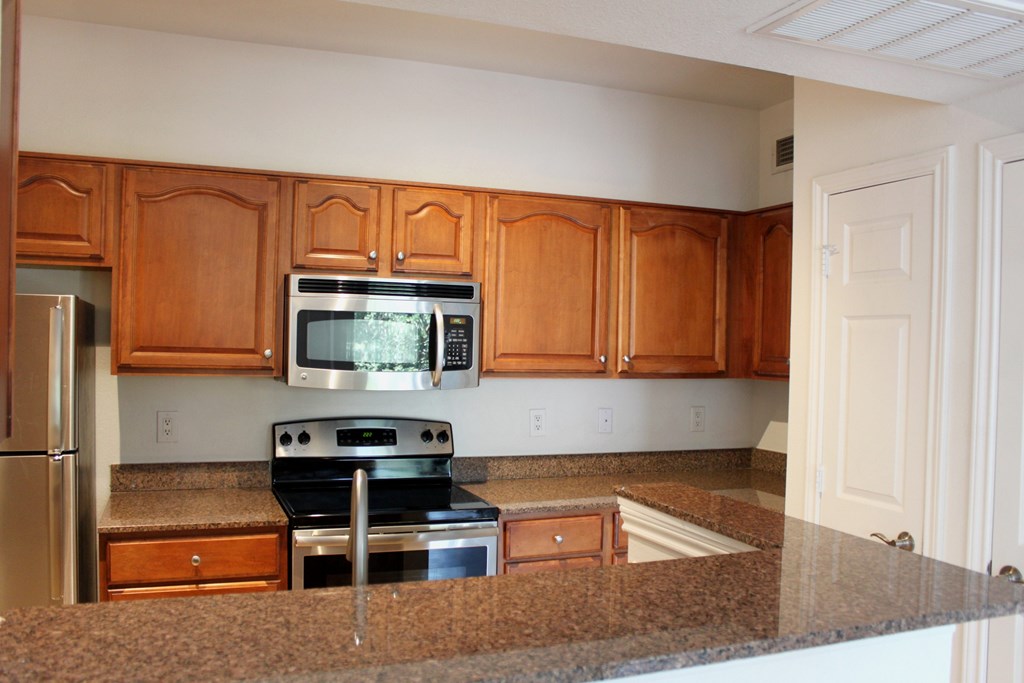 a kitchen with granite counter tops and wooden cabinets