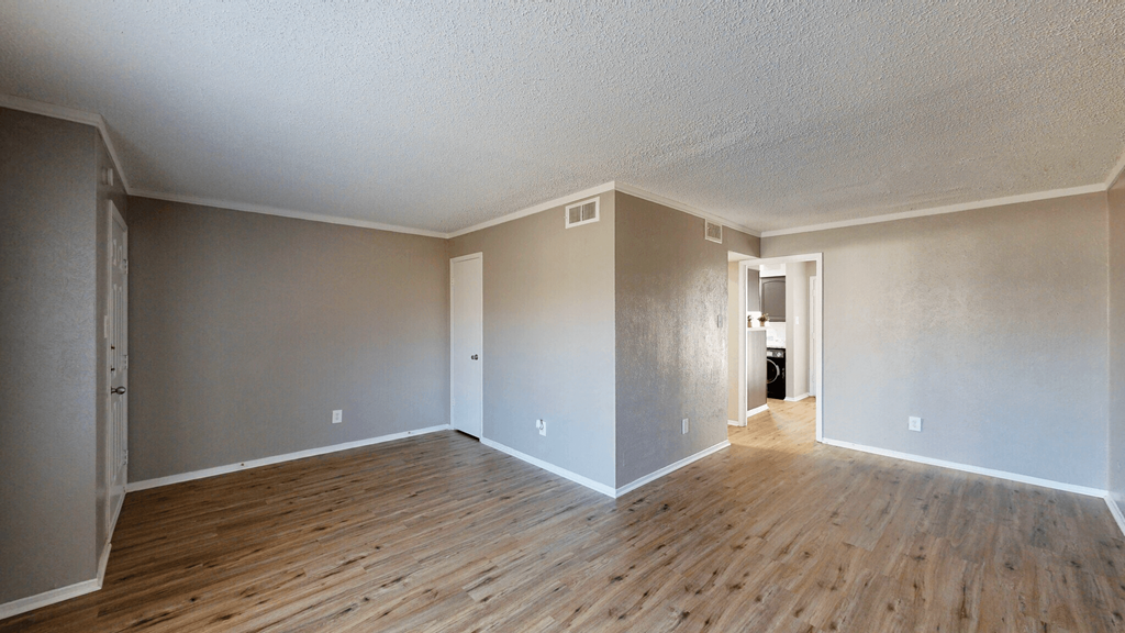 an empty living room with hardwood floors and grey walls