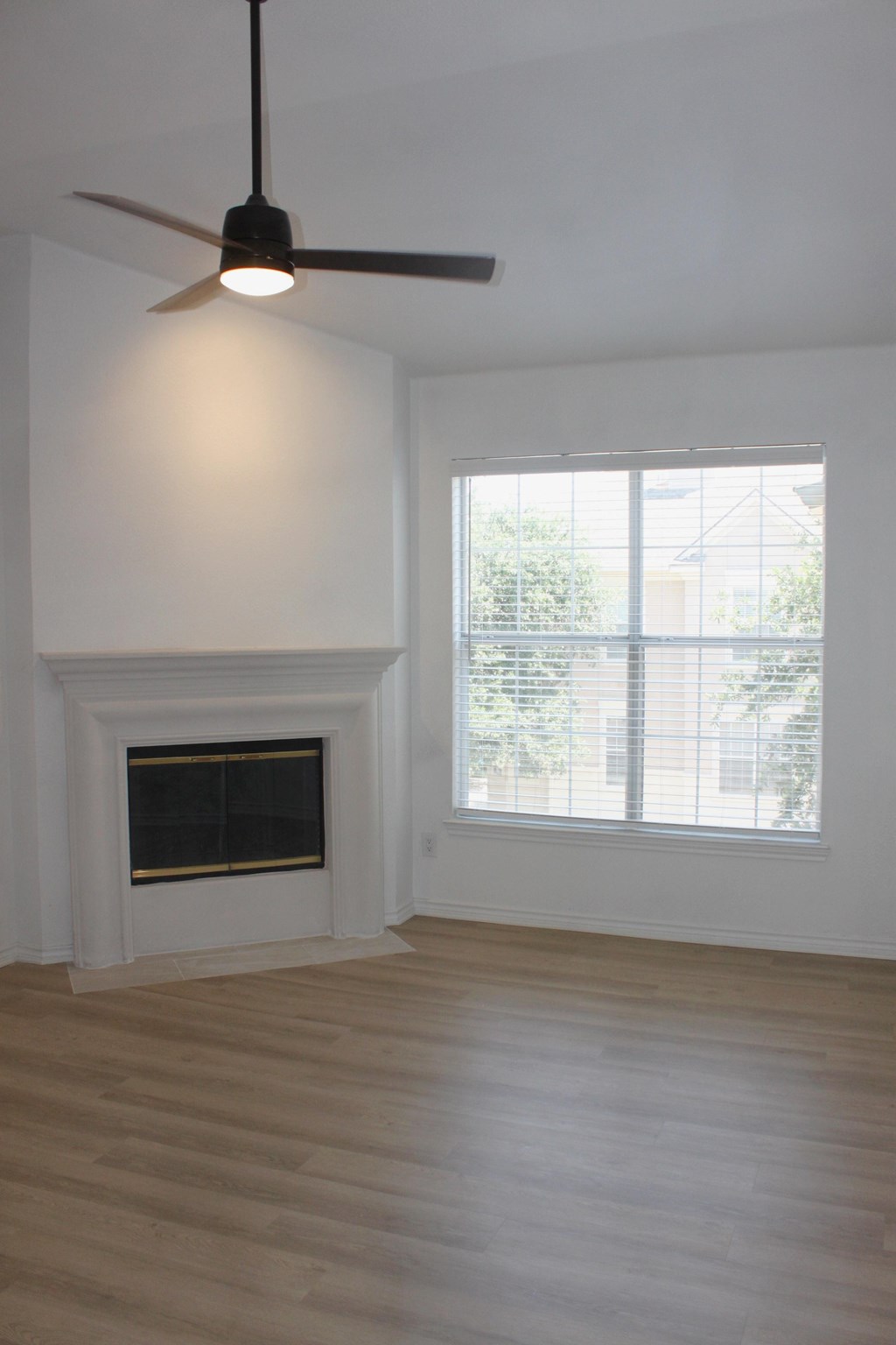an empty living room with a fireplace and a ceiling fan