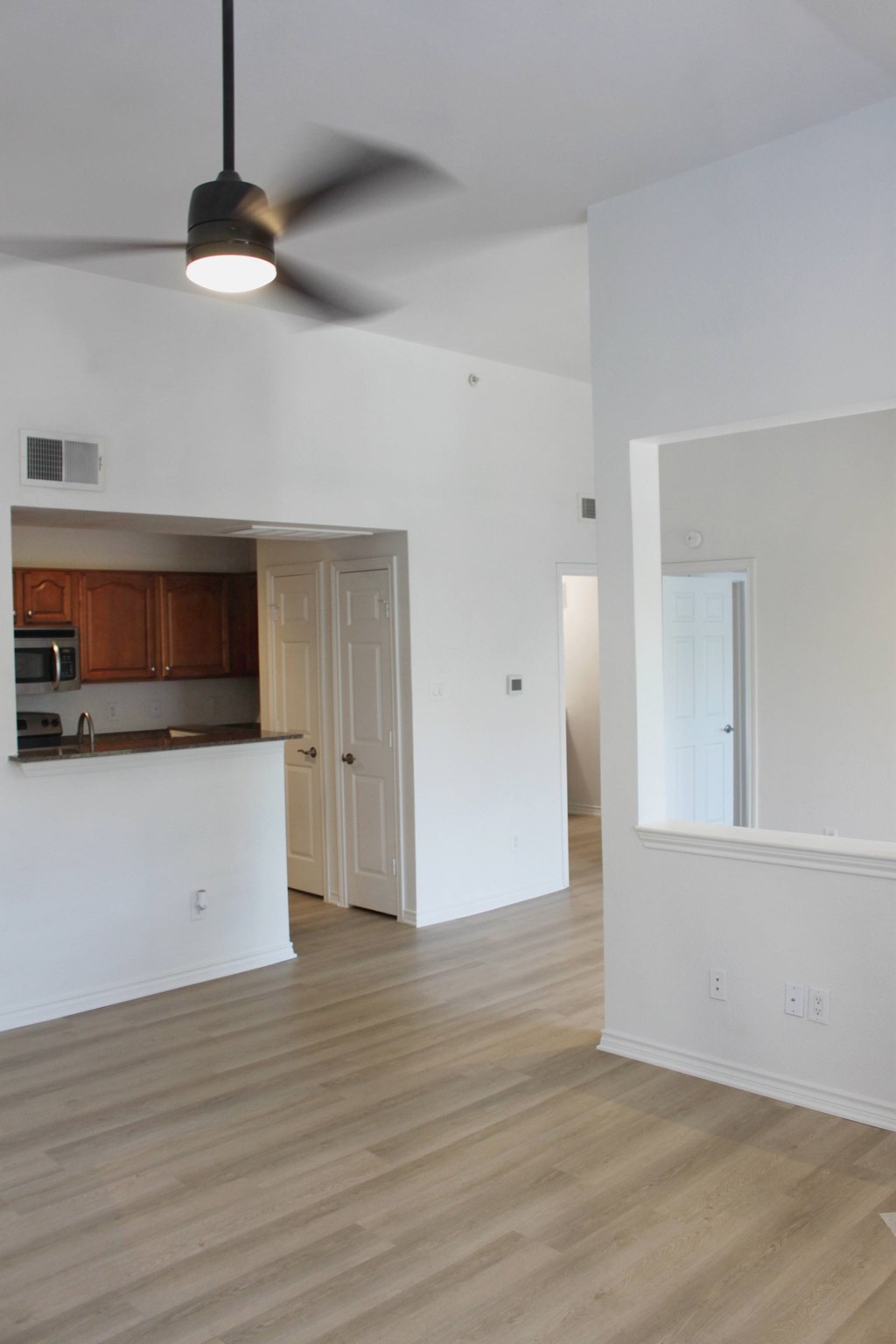 an empty living room and kitchen with a ceiling fan