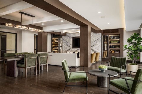 A modern dining room with a long table and green chairs.