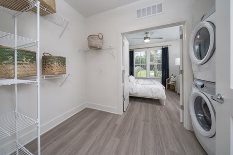 a laundry room with washer and dryer and a bed in a room with
