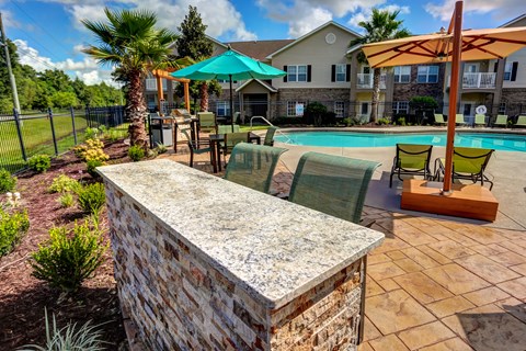 A pool area with a stone wall and a fence.