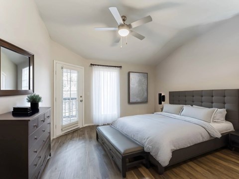 A bedroom with a bed, dresser, mirror, and window.