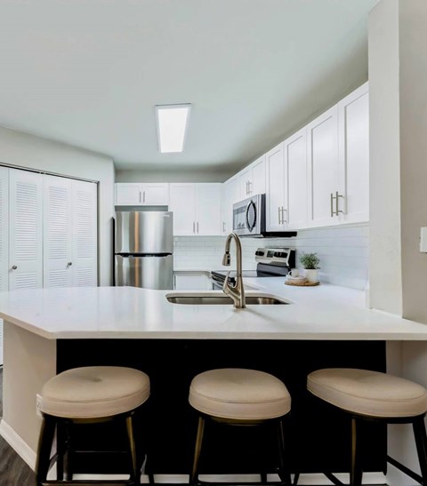 A kitchen with white cabinets and a white counter top.