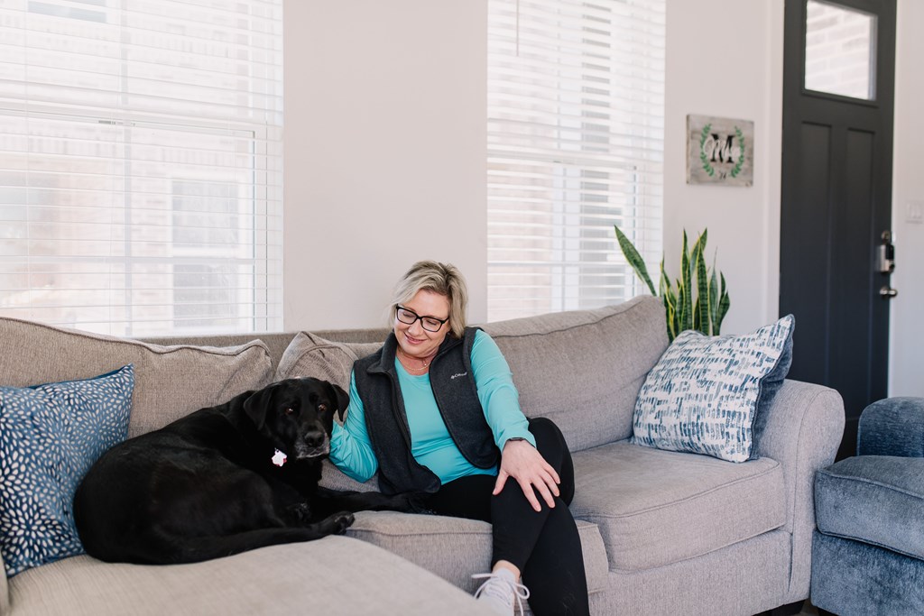 a woman sitting on a couch with a black dog