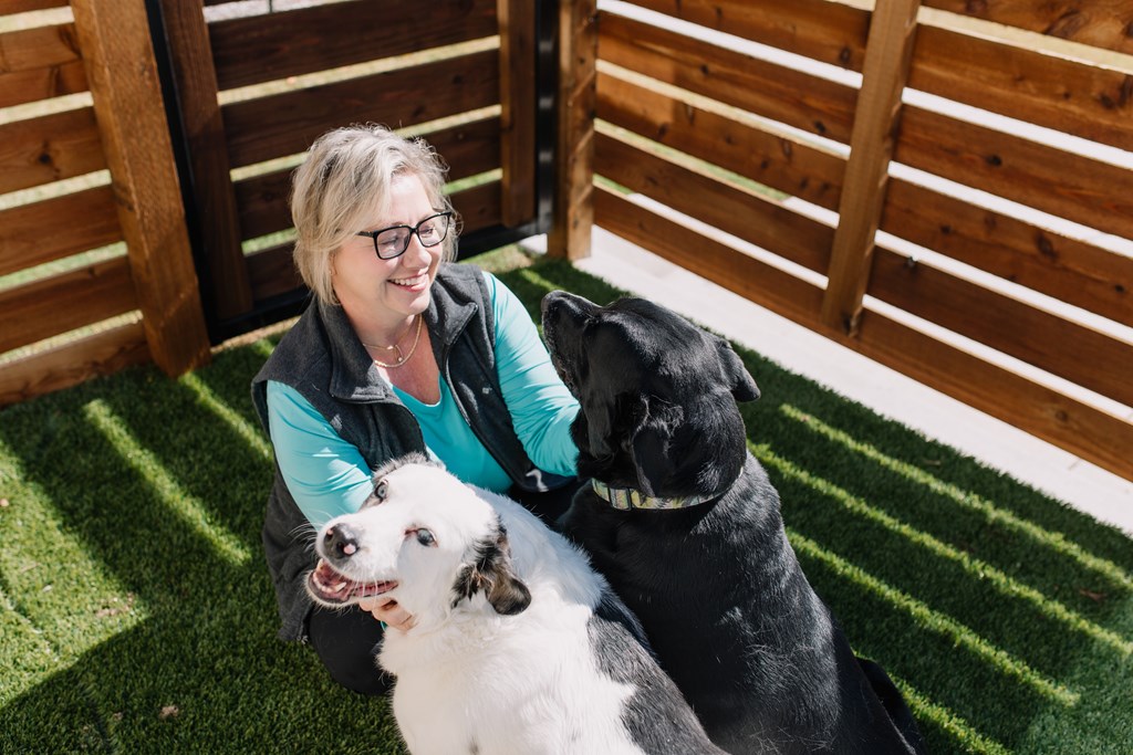a woman sitting on the grass with two dogs