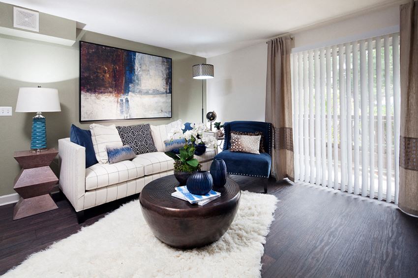 Ardenne Apartments model apartments with a white couch, blue chair and hardwood-style floor - Photo Gallery 1