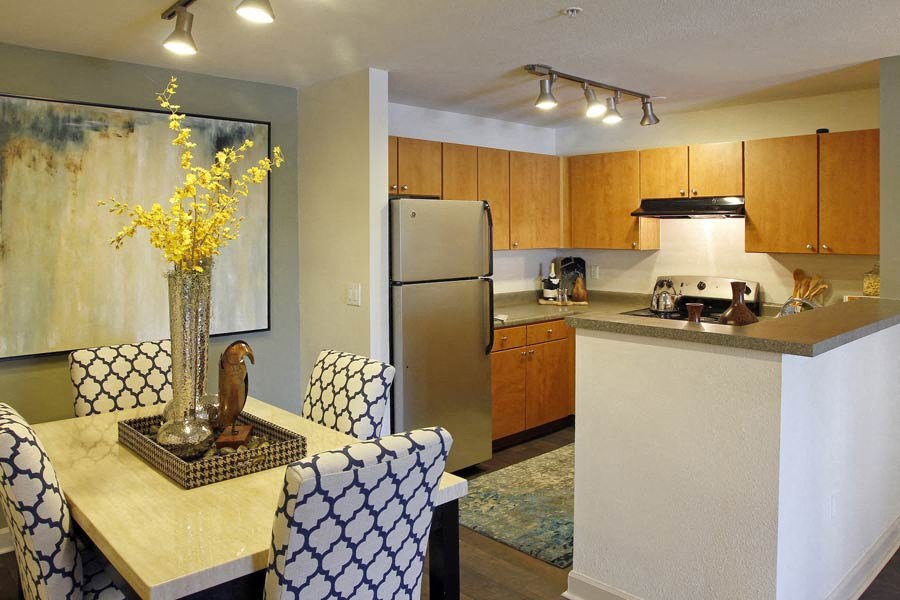 Ardenne Apartments kitchen and dining room with blue and white chairs, yellow flowers and stainless steel appliances