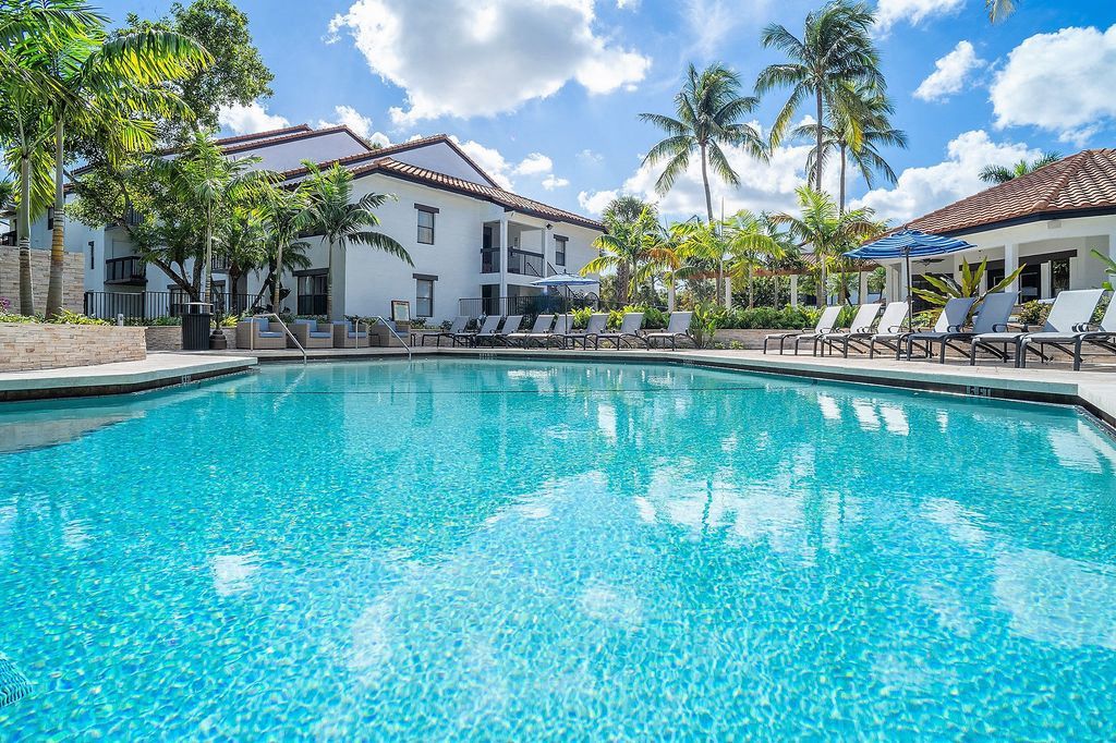 Pool with lounge chairs and apartment building in background