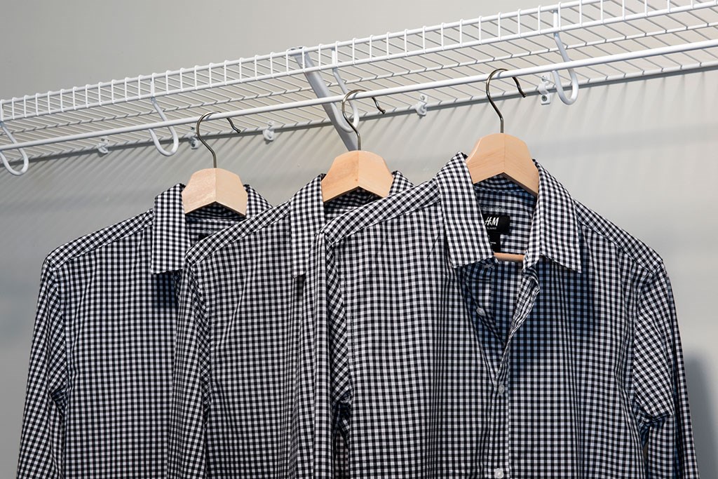 three shirts hanging on a rack in a closet