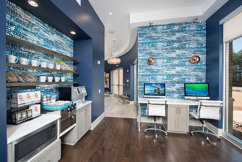 a home office with two computer desks and a blue wall with shelves