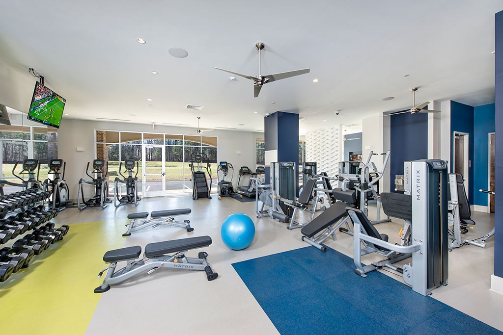 a gym with weights and cardio equipment and a television