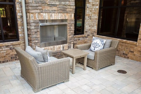 a patio with chairs and a table next to a fireplace