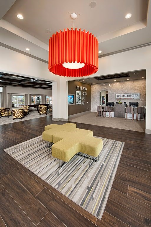 a lobby with a yellow couch and a large red chandelier