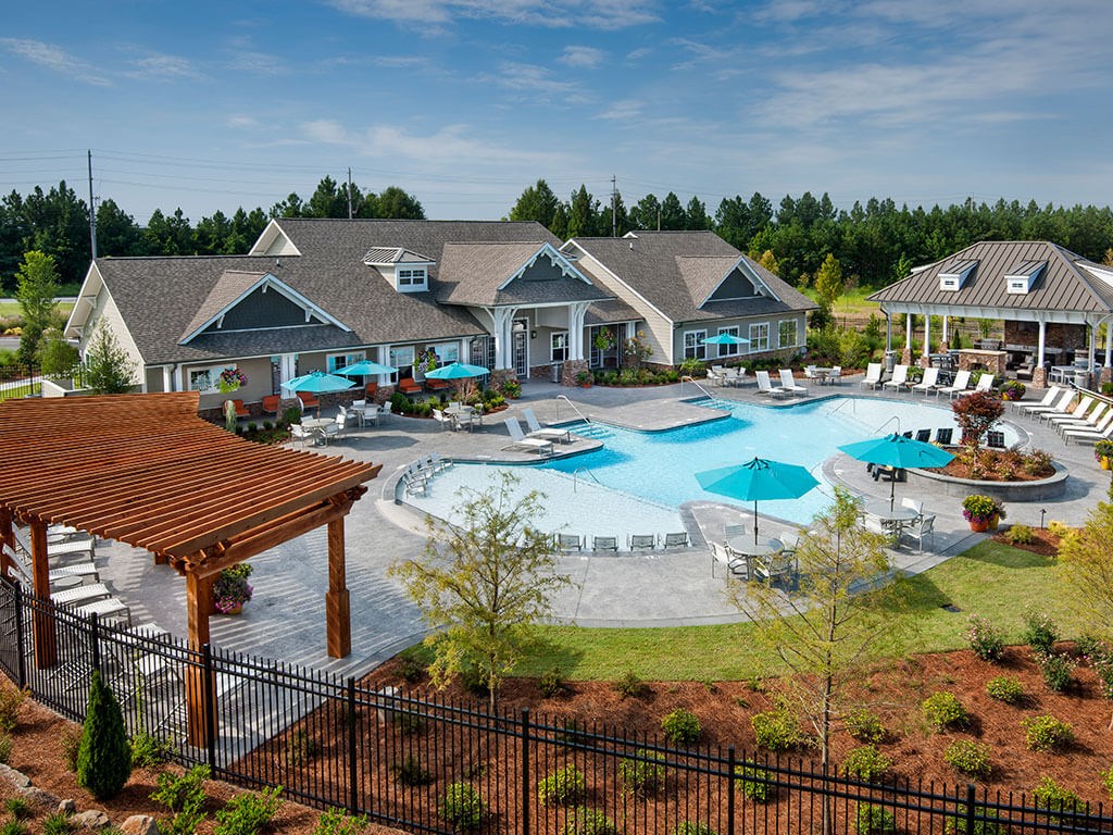 an aerial view of a large swimming pool with umbrellas and houses