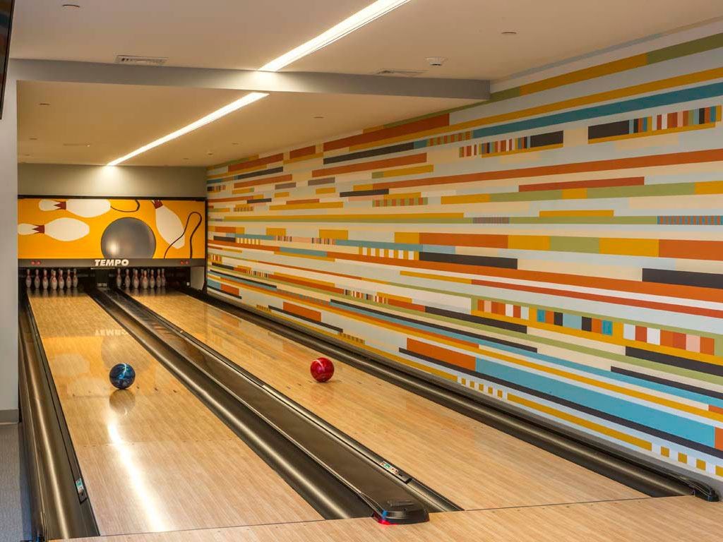 Bowling alley lanes with bowling balls rolling toward pins